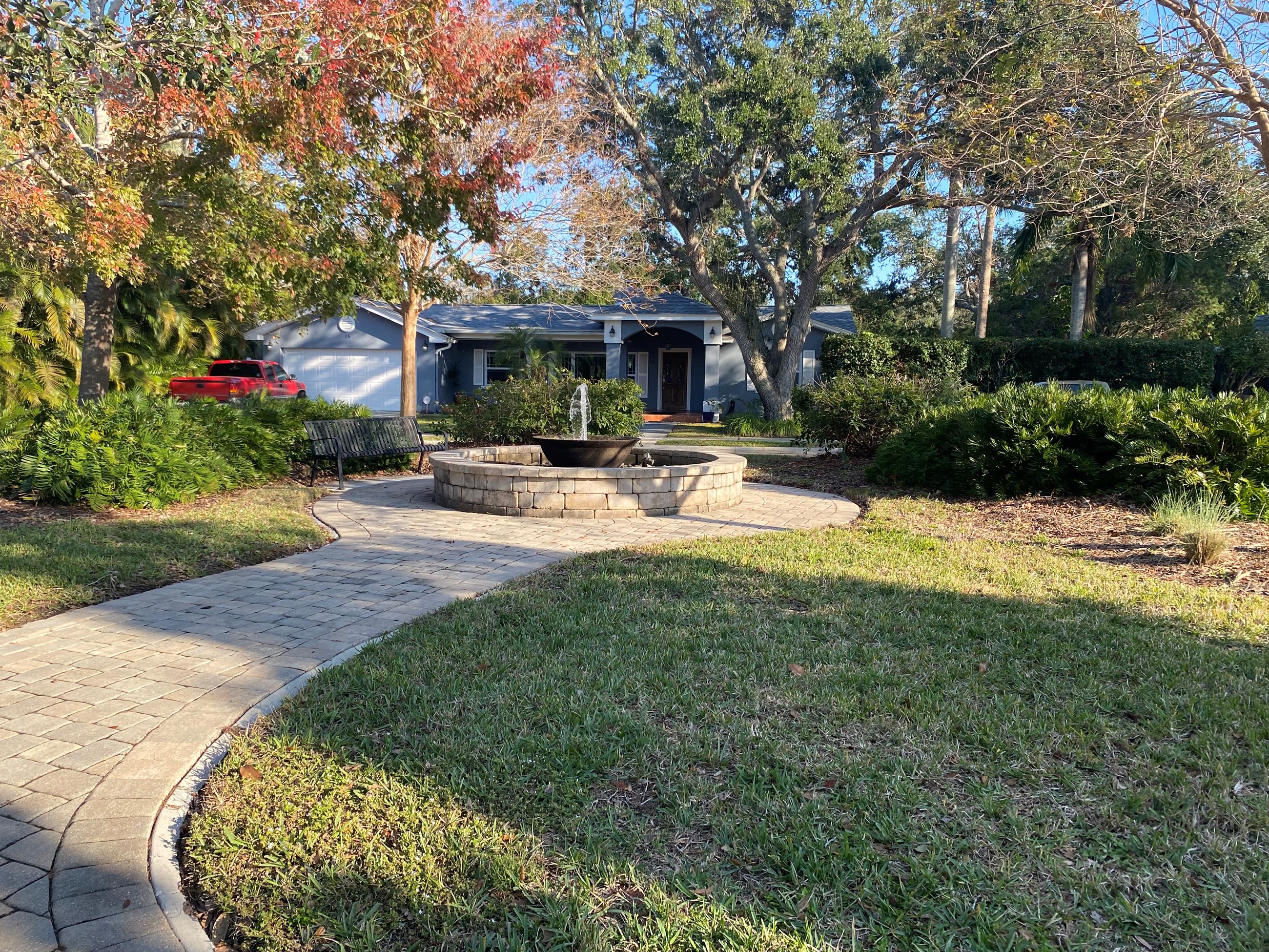 A curved path of pavers leads up to a flowing water fountain in Fountain Square Park.